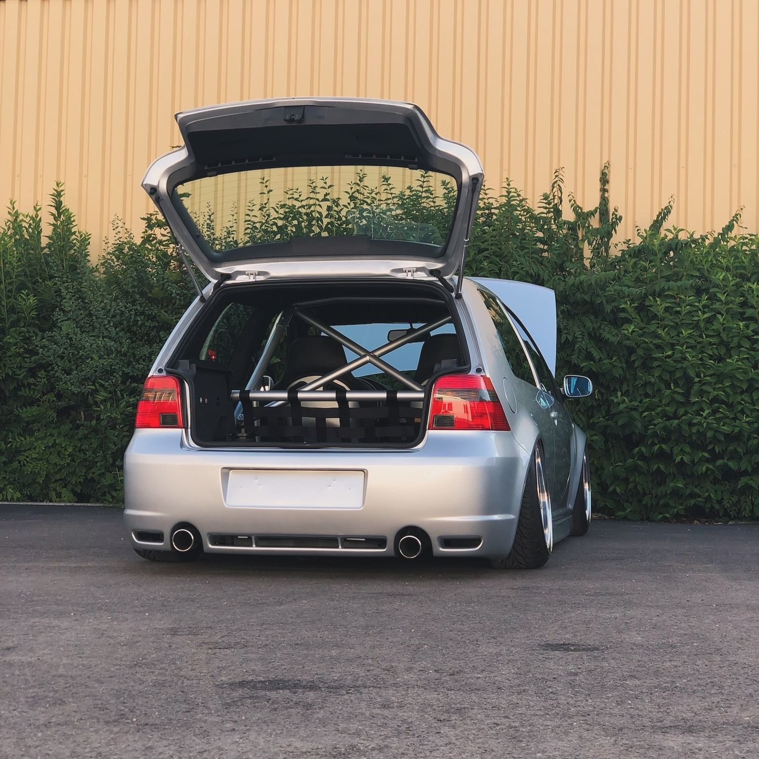 Silberner VW Golf IV R32 mit geöffneter Heckklappe vor einer Hecke